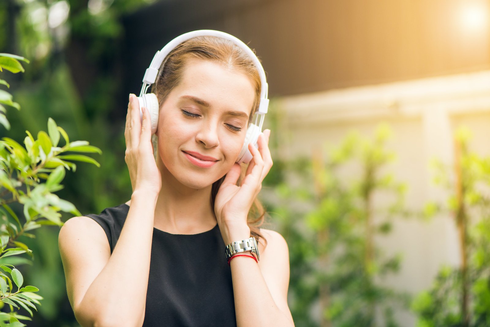 A woman holding headphones outdoors